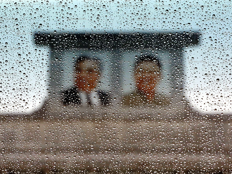 バスの窓越しに雨に煙る金日成主席(左)と金正日総書記の肖像画(本文と記事は関係ありません)=2013年、ロイター、北朝鮮・平壌の金日成スタジアム