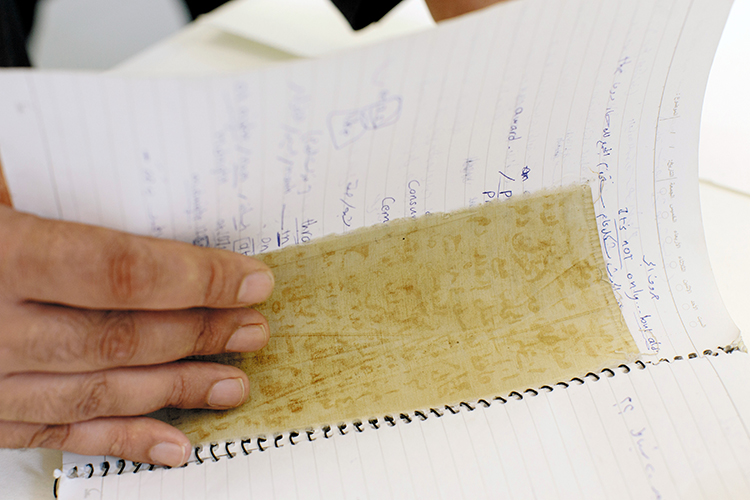 FILE -- Mansour Omari, who said he was imprisoned in Syria for human rights work, with a cloth scrap containing detainees