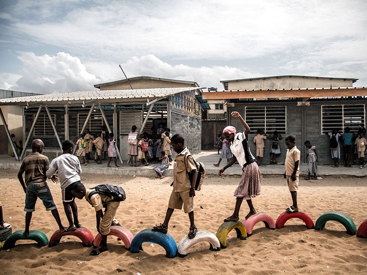 Students play on painted car tires outside their school, where the buildings are made out of plastic bricks, in Abidjan, Ivory Coast, June 24, 2019. Plastic garbage collected by a women's group is being recycled into bricks and used to build schools in West Africa. (Yagazie Emezi/The New York Times)