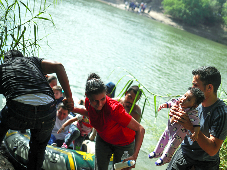 Family units from Central America await their turn on the Mexico side of Rio Grande river as Eliani Valentin, a five-month-old girl from Honduras, is held by a man after a group used a raft to illegally cross into the U.S. from Mexico in Granjeno, Texas, October 5, 2018. Reuters photographer Adrees Latif: