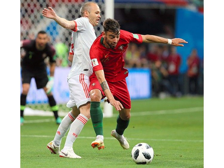 サッカーW杯ロシア大会で、ポルトガルのB・フェルナンデス(右)にプレッシャーをかけるスペインのイニエスタ=長島一浩撮影