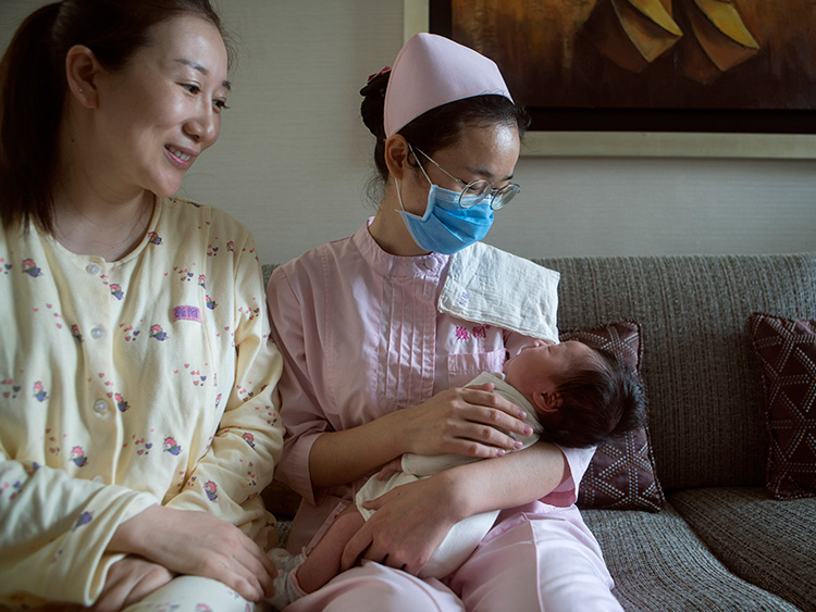 北京の私立病院で生後1カ月の乳児を抱く病院スタッフ=2018年8月3日、Giulia Marchi/©2018 The New York Times