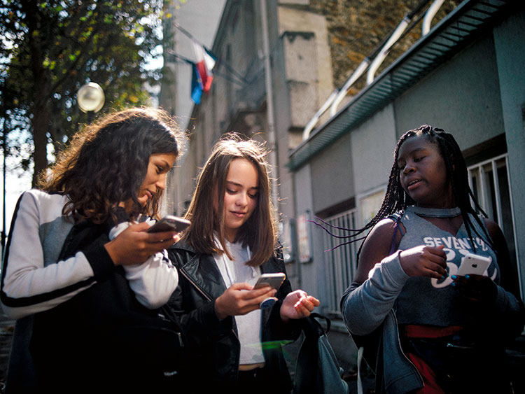 放課後、さっそくスマホを使うパリ市内の中学生。左からイマーン・ベラルッシ、ゾエリン・マッソン、グレース・ブラウルー=2018年9月19日、Dmitry Kostyukov/©2018 The New York Times