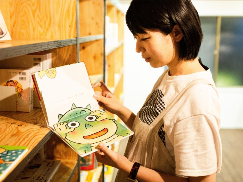 夢眠書店の本棚で絵本を手にする夢眠ねむさん