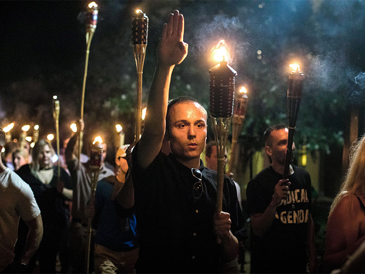 FILE -- A man raises his arm in a Nazi salute at a gathering of white nationalists in Charlottesville, Va., Aug. 11, 2017. Around the world, long-dominant groups see themselves as under siege, driving the rise of right-populism, religious nationalism and white terrorism. (Edu Bayer/The New York Times)
