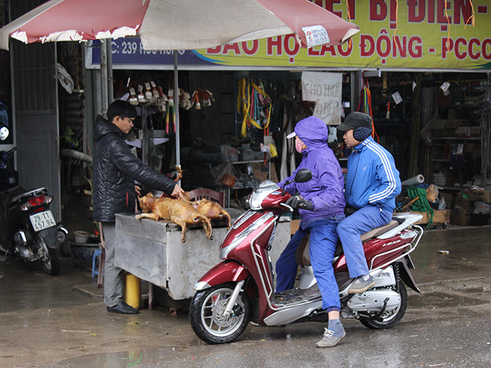 ハノイ市郊外ハタイの通りで丸焼きの犬を買う客(鈴木暁子撮影)