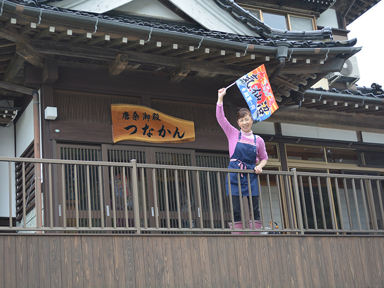 大漁旗で客を見送る民宿「唐桑御殿つなかん」の菅野一代=宮城県気仙沼市、本間沙織撮影
