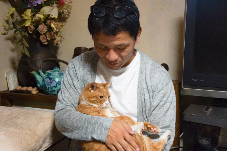齋藤さん宅で、マメを抱く上村さん 「普通のおじいちゃん猫として、余生をのんびり過ごしてね。僕は犬や猫の力になれるような写真をこれからも撮りたいよ」