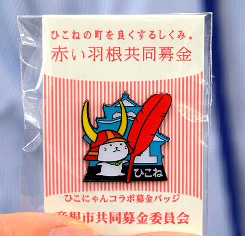 赤い羽根を持ったひこにゃんのバッジ=彦根市