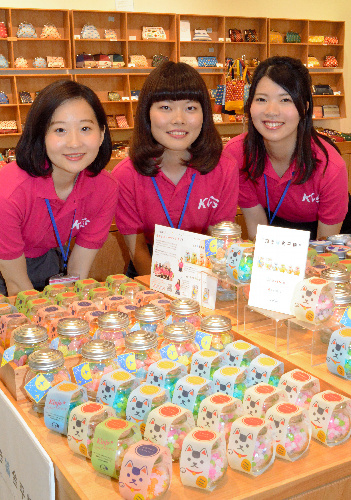 「そらみせ」の店頭に並んだ「招き猫金平糖」などの商品と、企画に携わった金城学院大の学生たち=愛知県常滑市の中部空港