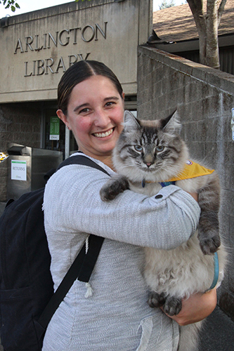 アーリントン図書館の前で、セラピー猫タイを抱っこするハンドラーで飼い主のジェニー