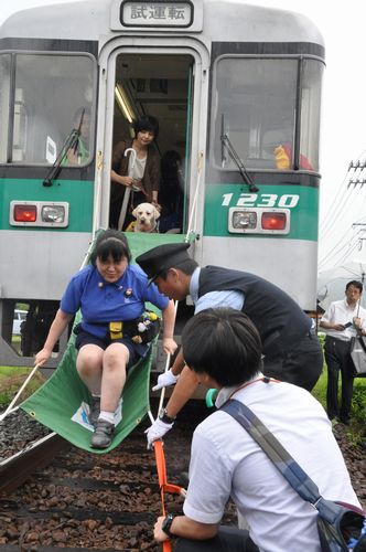 避難シューターを使った訓練をする鶴野さんら=阿南市のJR牟岐線