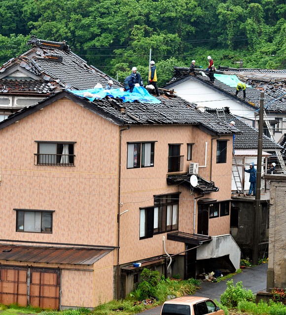 山形县鹤冈市小岩川,雨中,作业人员们为瓦砾掉落的屋顶铺盖上罩布=摄