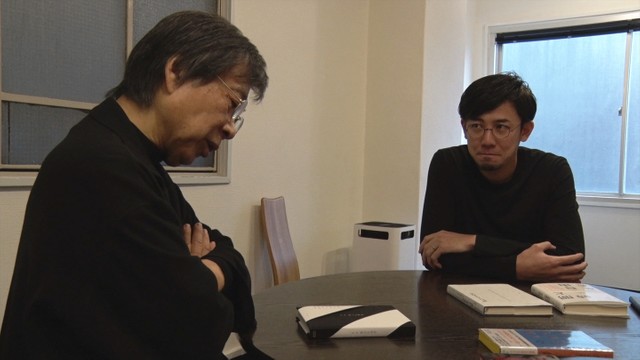 水戸部功（右）の装幀に首を傾げる菊地信義（©2019「つつんで、ひらいて」製作委員会）